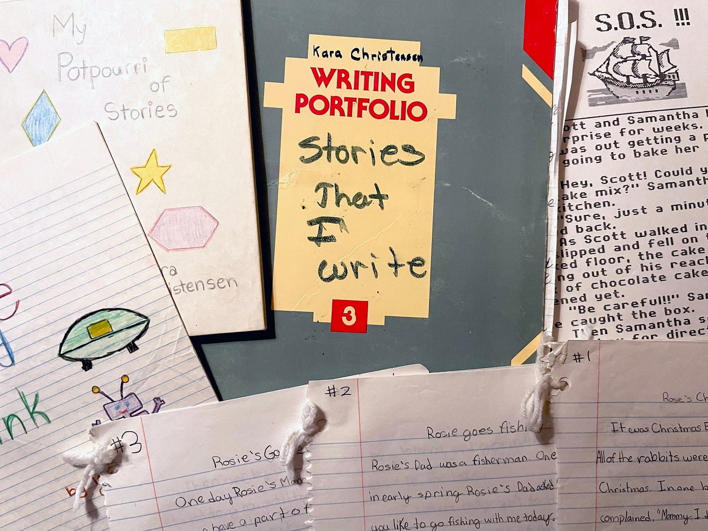 Aerial view of various papers and folders with childlike handwriting and stories.