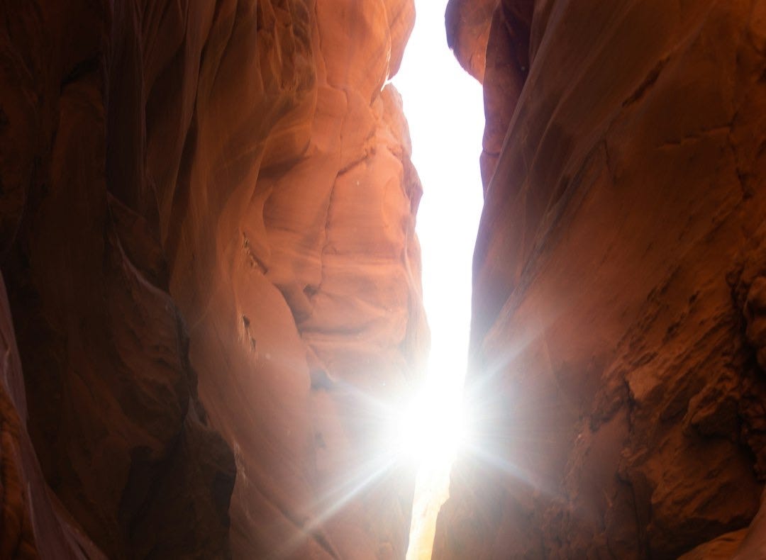 a light shines through a narrow slot in a rock formation a light shines through a narrow slot in a rock formation