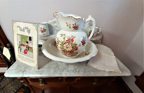 A gallery at the Country Doctor Museum set up as a "sick room" showing a bed and other articles that might be found, including a flower-painted pitcher and basin for washing up, and Mrs. Winslow's medicine advertisement.