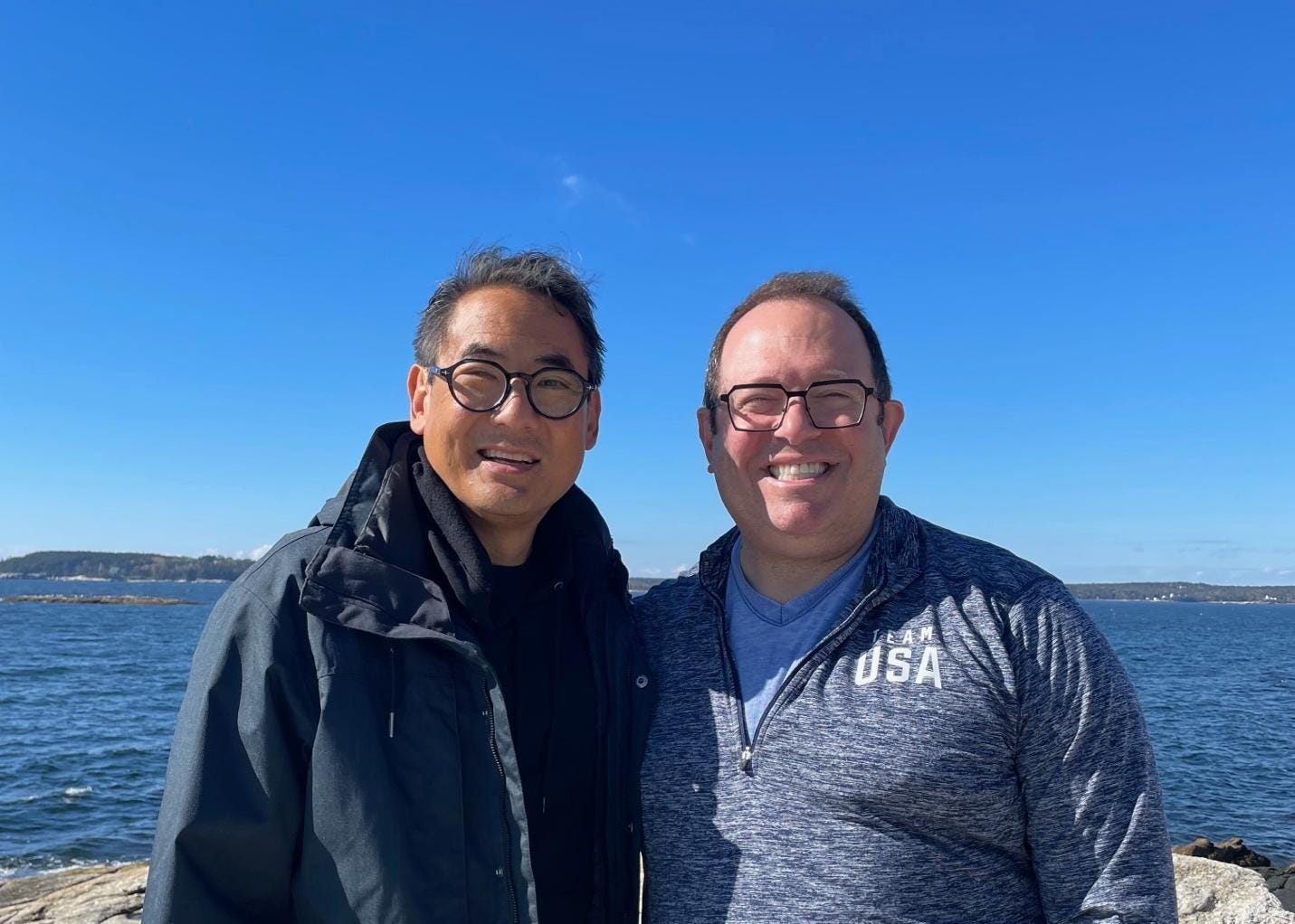 Stephen Pao (left) and Elliot Schwartz (right), smiling on the rocky Maine coast in 2023 under a clear blue sky, Elliot in his Team USA pullover. Stephen Pao (left) and Elliot Schwartz (right), smiling on the rocky Maine coast in 2023 under a clear blue sky, Elliot in his Team USA pullover.