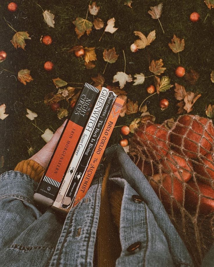 This may contain: a person is laying on the ground with their legs crossed and holding three books in front of them