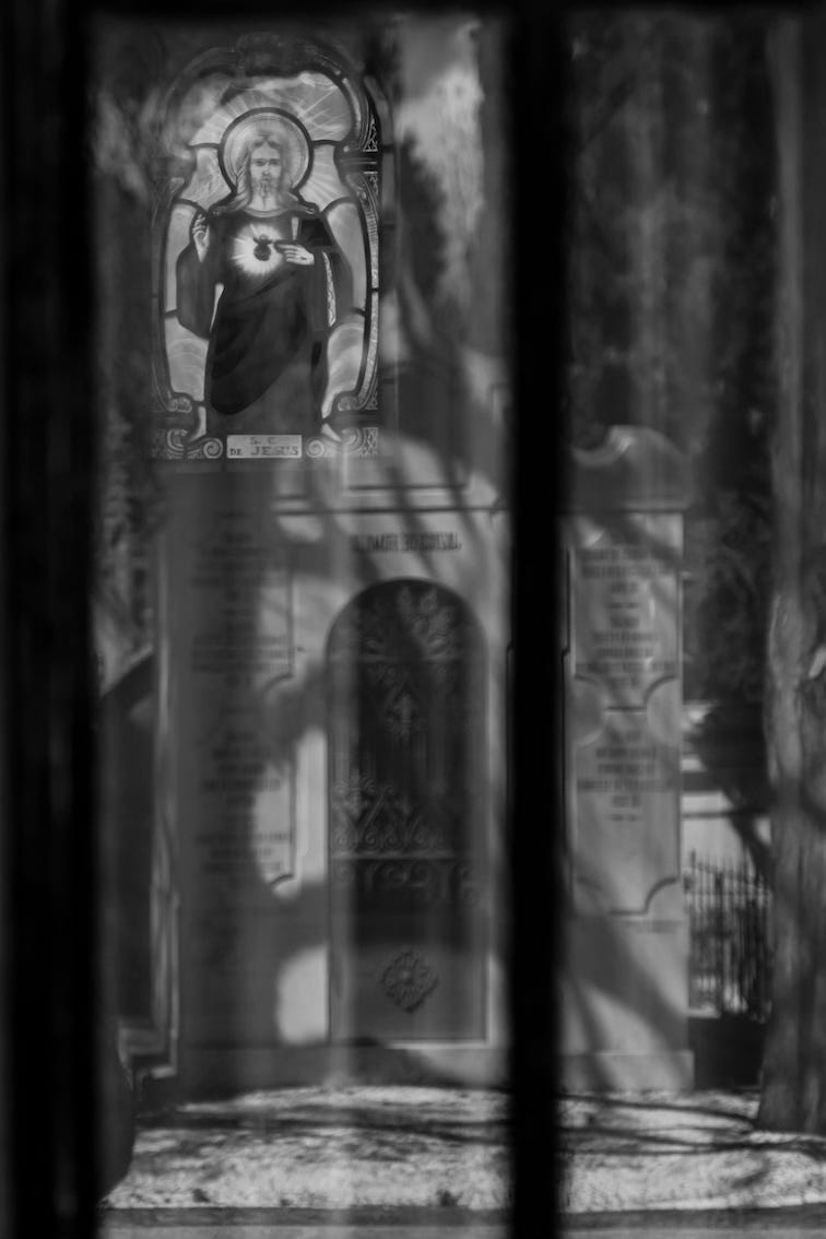 through a veil one sees a painted glass image of the Christ inside a tomb in a Lisbon cemetery