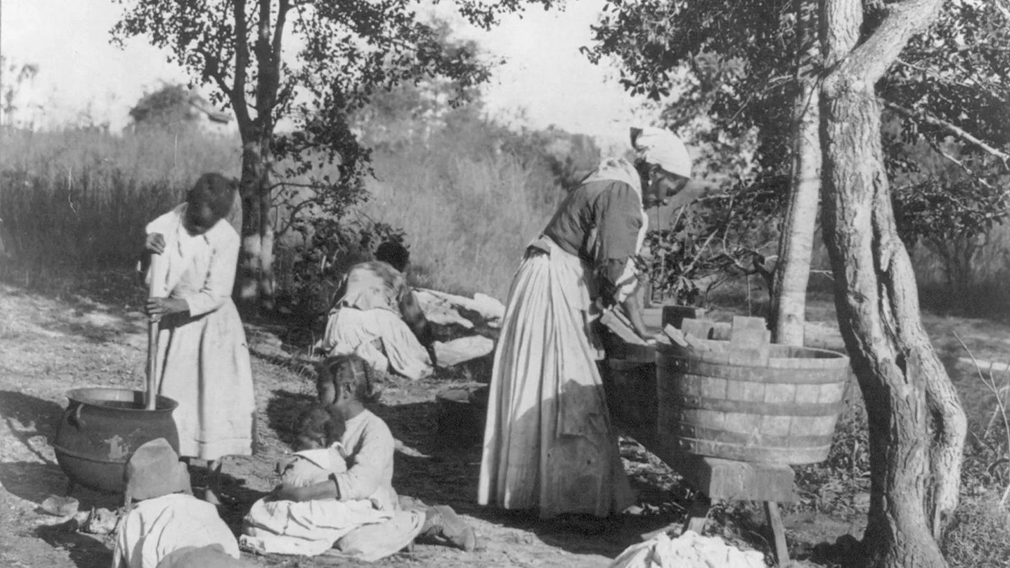 Library of Congress photo description: 'African-American woman doing laundry with a scrub board and tub, African-American girl stirring pot with 3 other children on the ground watching, and a woman in the background spreading laundry' Library of Congress photo description: 'African-American woman doing laundry with a scrub board and tub, African-American girl stirring pot with 3 other children on the ground watching, and a woman in the background spreading laundry'