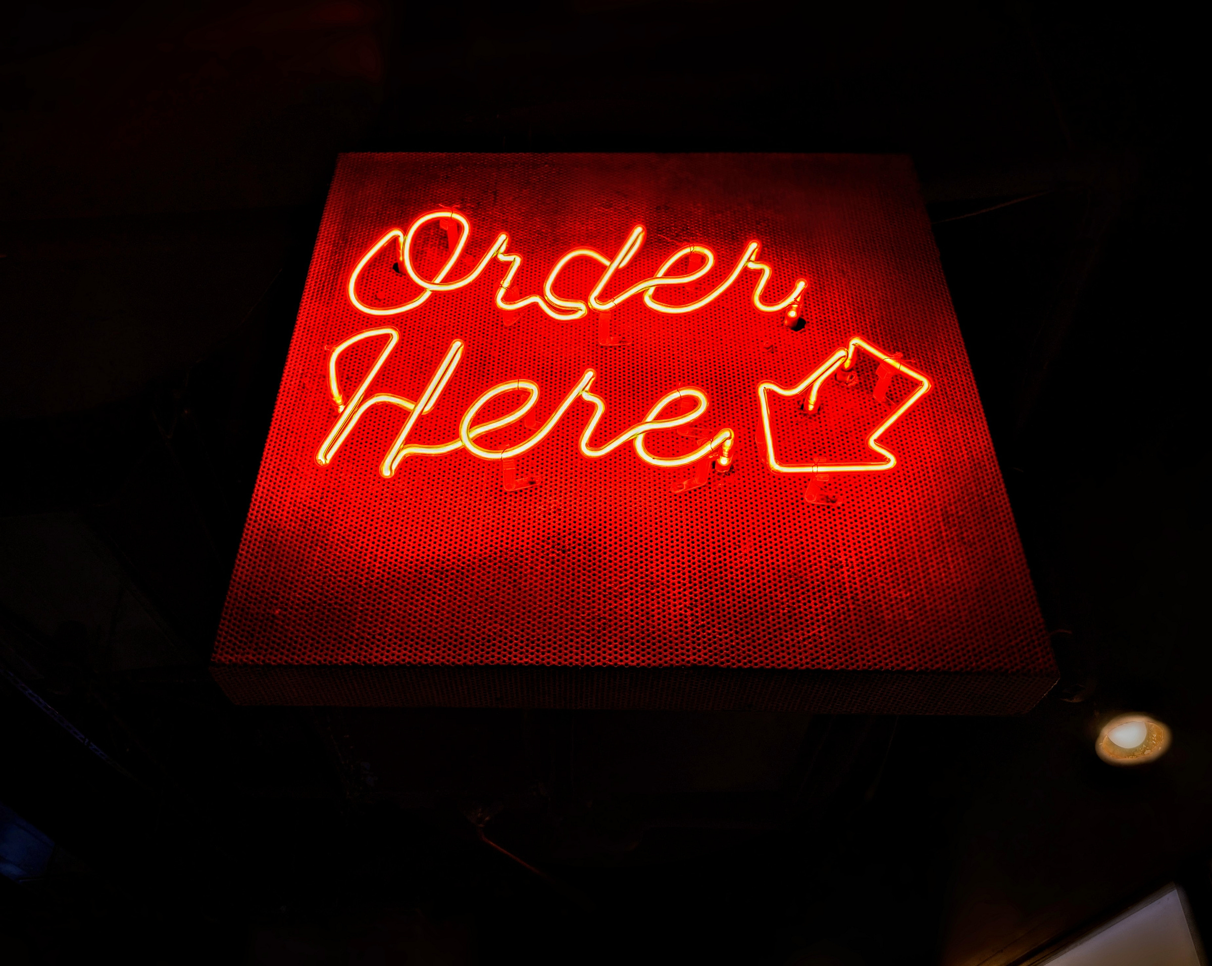 Red sign that says order here with arrow pointing at the bottom. Red sign that says order here with arrow pointing at the bottom.