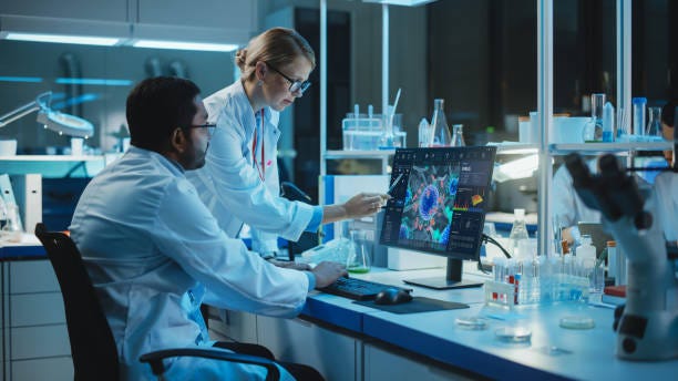 Female Research Scientist with Bioengineer Working on a Personal Computer with Screen Showing Virus Analysis Software User Interface. Scientists Developing Vaccine, Drugs and Antibiotics in Laboratory Female Research Scientist with Bioengineer Working on a Personal Computer with Screen Showing Virus Analysis Software User Interface. Scientists Developing Vaccine, Drugs and Antibiotics in Laboratory pharmaceutical laboratory stock pictures, royalty-free photos & images