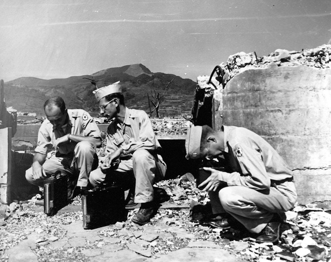 three Manhattan Project specialists use Geiger counters to measure residual radioactivity