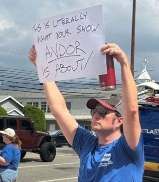 May be a meme of 2 people, people standing, poster, banner and text