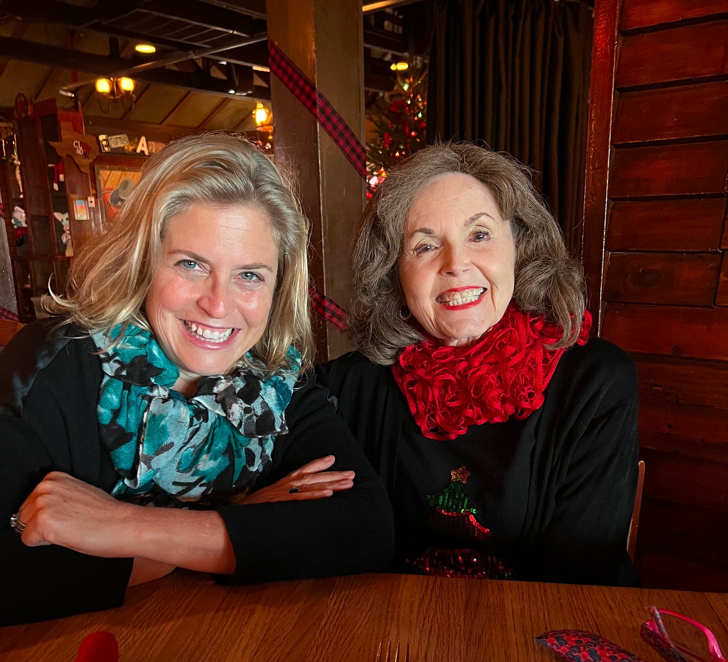 two women at a table wearing black blouses and large scarves