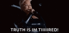 a woman in a black dress is singing into a microphone and saying `` truth is im tiiiiired ! ''
