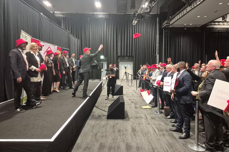 Steve Reed on stage throwing hats to an audience