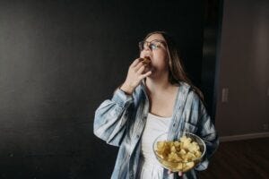 plump woman eating potato chips