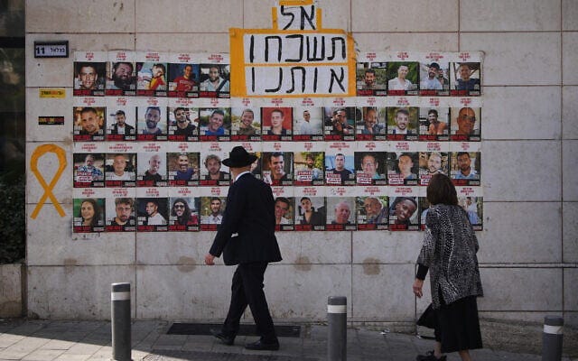 People look at photos of hostages held by Hamas in Gaza, in Jerusalem, October 4, 2025. The Hebrew sign reads, "don't forget us." (AP Photo/Ohad Zwigenberg)