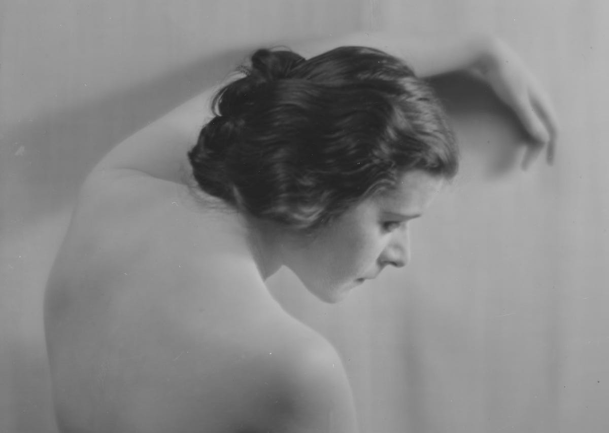 Publicity photo of Theda Bara seen from behind, with her arms and shoulders bare. 