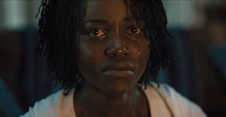 This may contain: a woman with dreadlocks stares at the camera while standing in front of a dark background