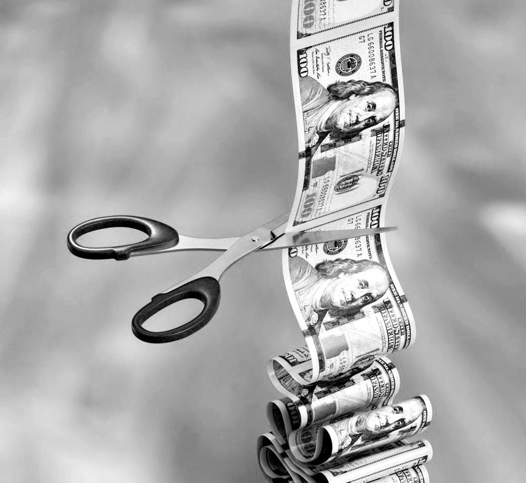 a stack of money sitting next to a pair of scissors
