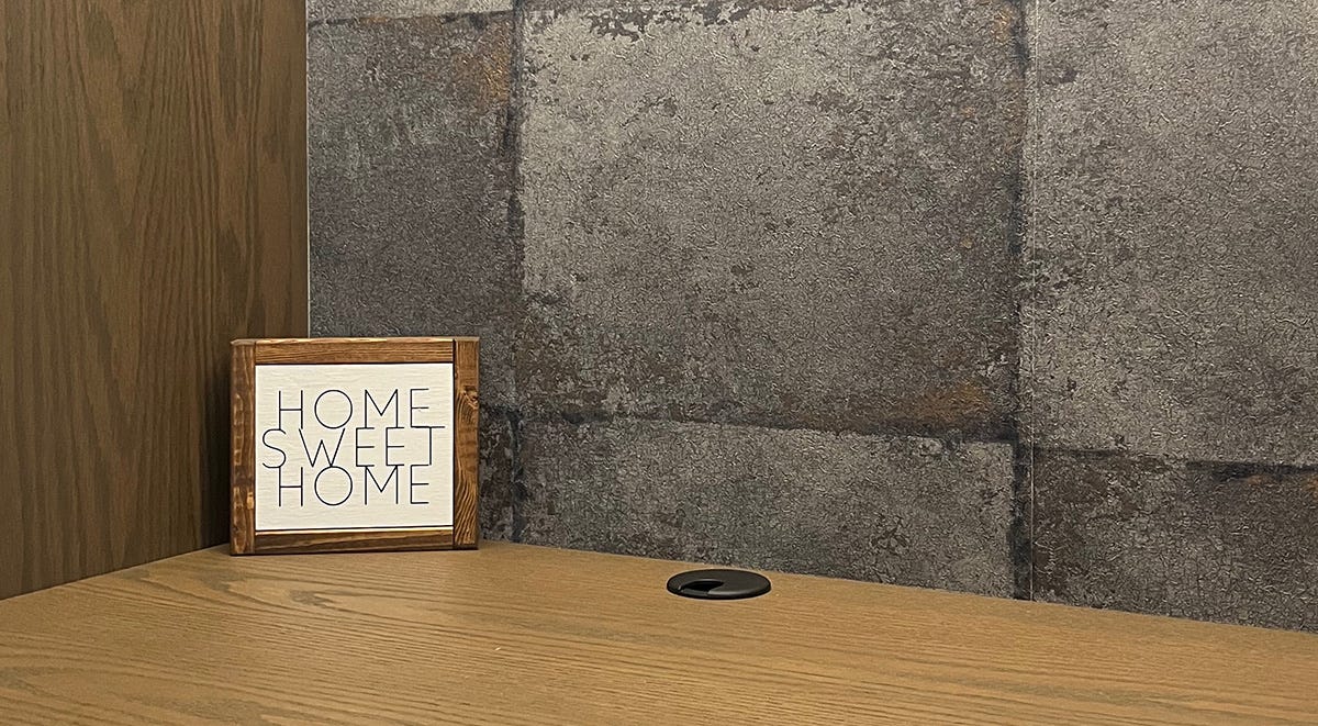 Small wooden sign on a desk that reads "Home Sweet Home"