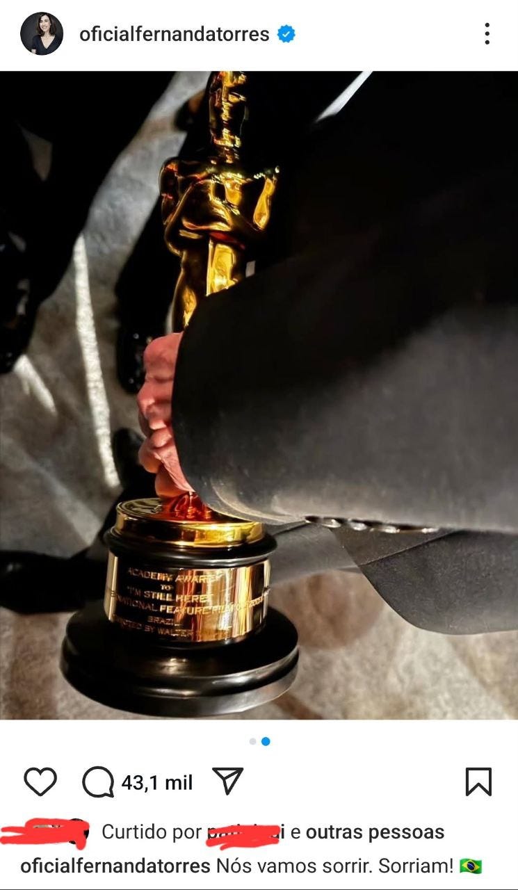 Post na conta de Instagram da Fernanda Torres (@oficialfernandatorres) com a foto de uma mão segurando o Oscar do Brasil. Dá pra ver que está gravado I'm Still Here na base da estatueta dourada. A mão é de um braço usando terno preto e a legenda traz "Nós vamos sorrir. Sorriam!", que é uma frase icônica do filme.