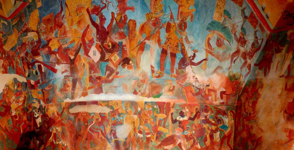 A large mural depicts a chaotic battle with numerous people, either shirtless or wearing animal skins, yelling while holding up spears or their fists. A large mural depicts a chaotic battle with numerous people, either shirtless or wearing animal skins, yelling while holding up spears or their fists.