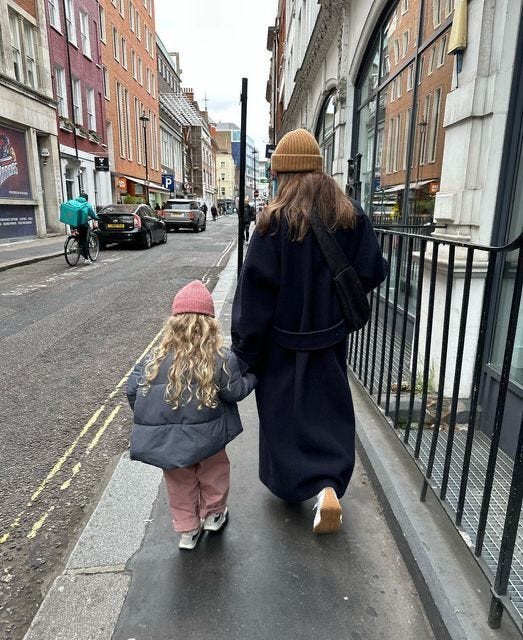 This may contain: a woman and child are walking down the street