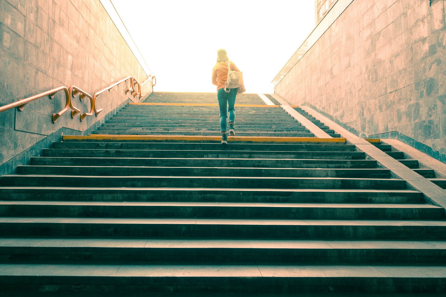 Woman climbing steps towards the light: Beneath the obvious is a profound principle.