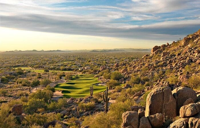 This may contain: a golf course in the desert with rocks and cactuses on it's side This may contain: a golf course in the desert with rocks and cactuses on it's side
