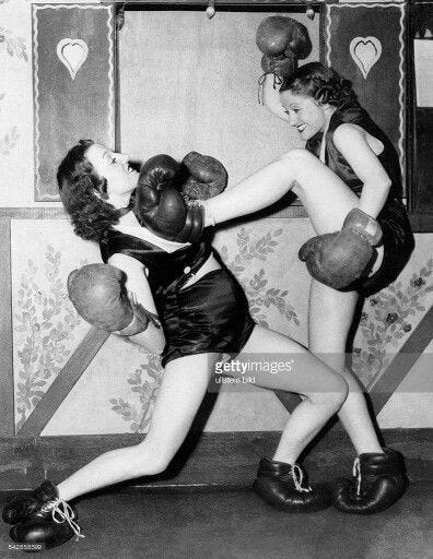 This may contain: two young women boxing in an old fashion photo, one is wearing gloves and the other has