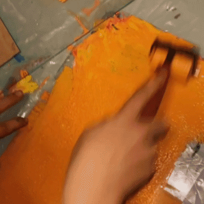 Child's hand pressing inked foam block onto blue paper Hands rolling orange ink onto a brayer Child rolling brayer over foam printing block Hand holding carved foam block with orange ink