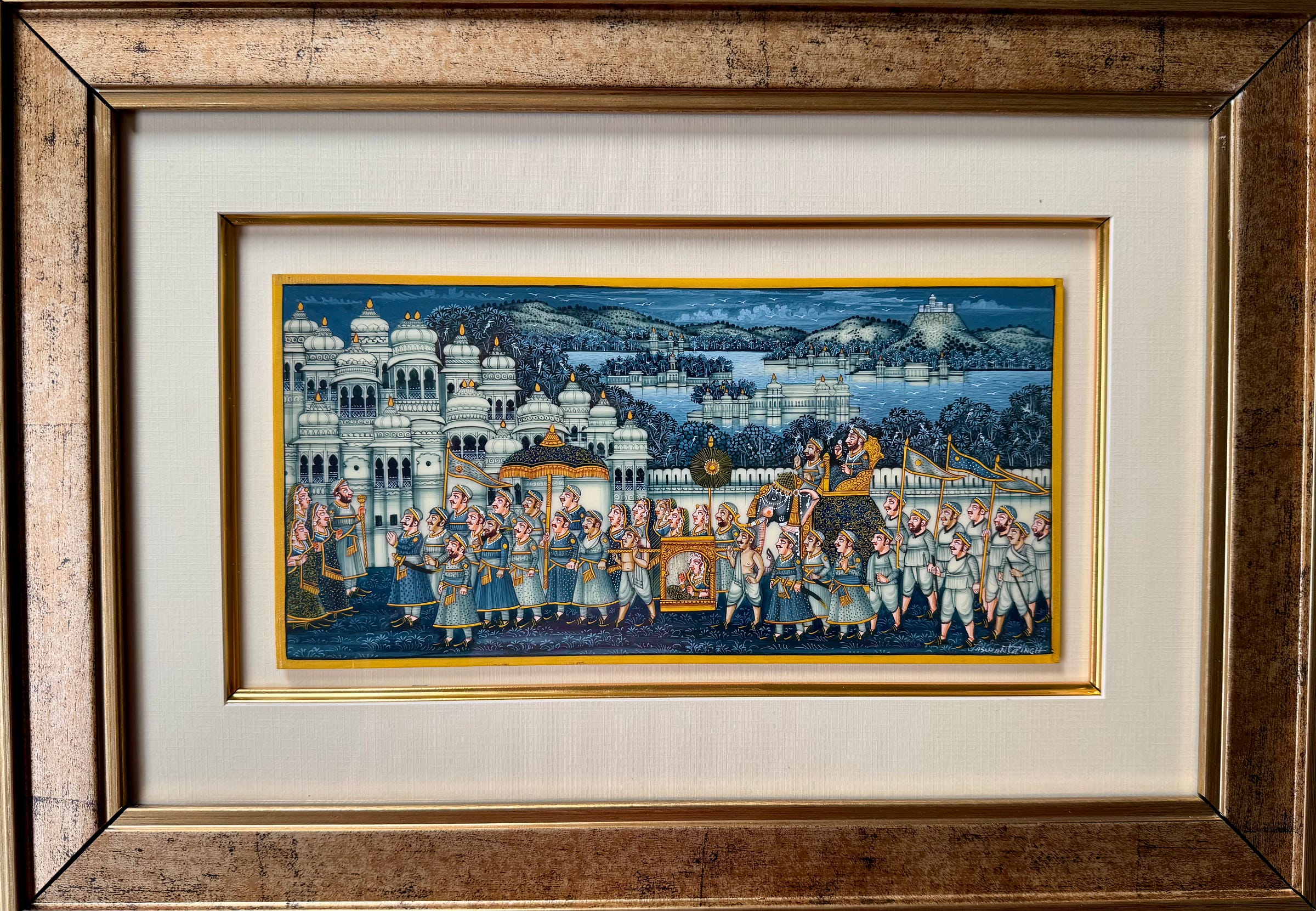 Framed miniature painting showing a procession scene with architectural and landscape elements.