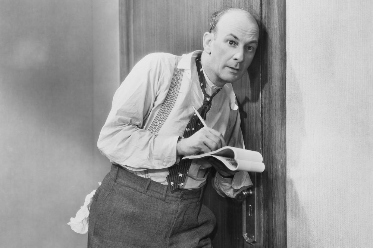 Man listening at a door and taking notes.