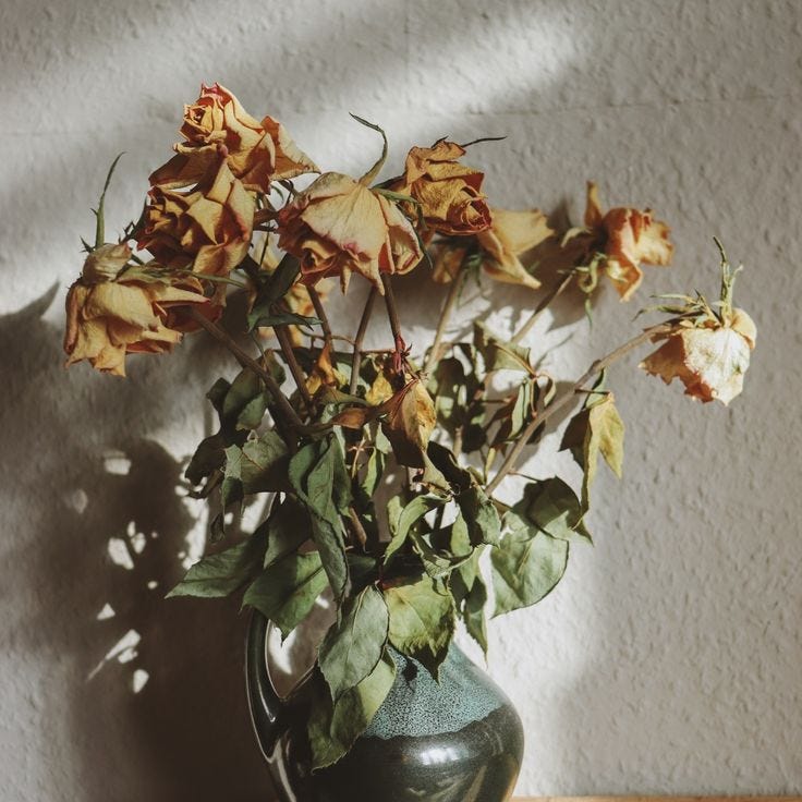 This may contain: a vase filled with lots of flowers on top of a wooden table next to a wall