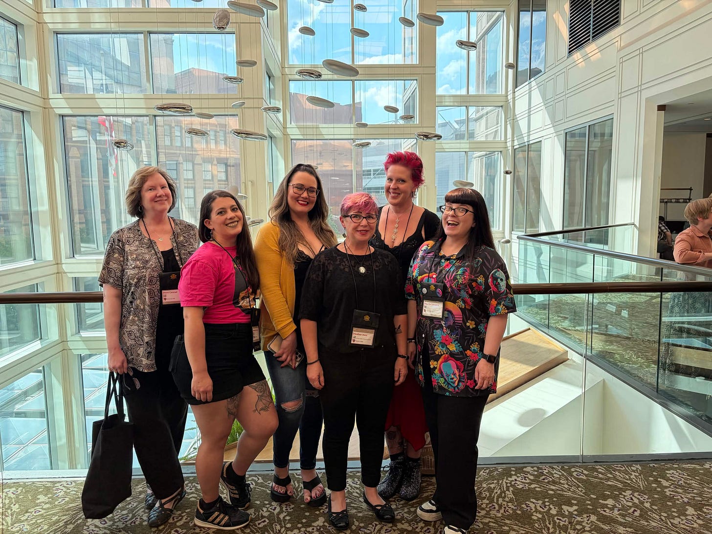 Six women standing in a glass lobby