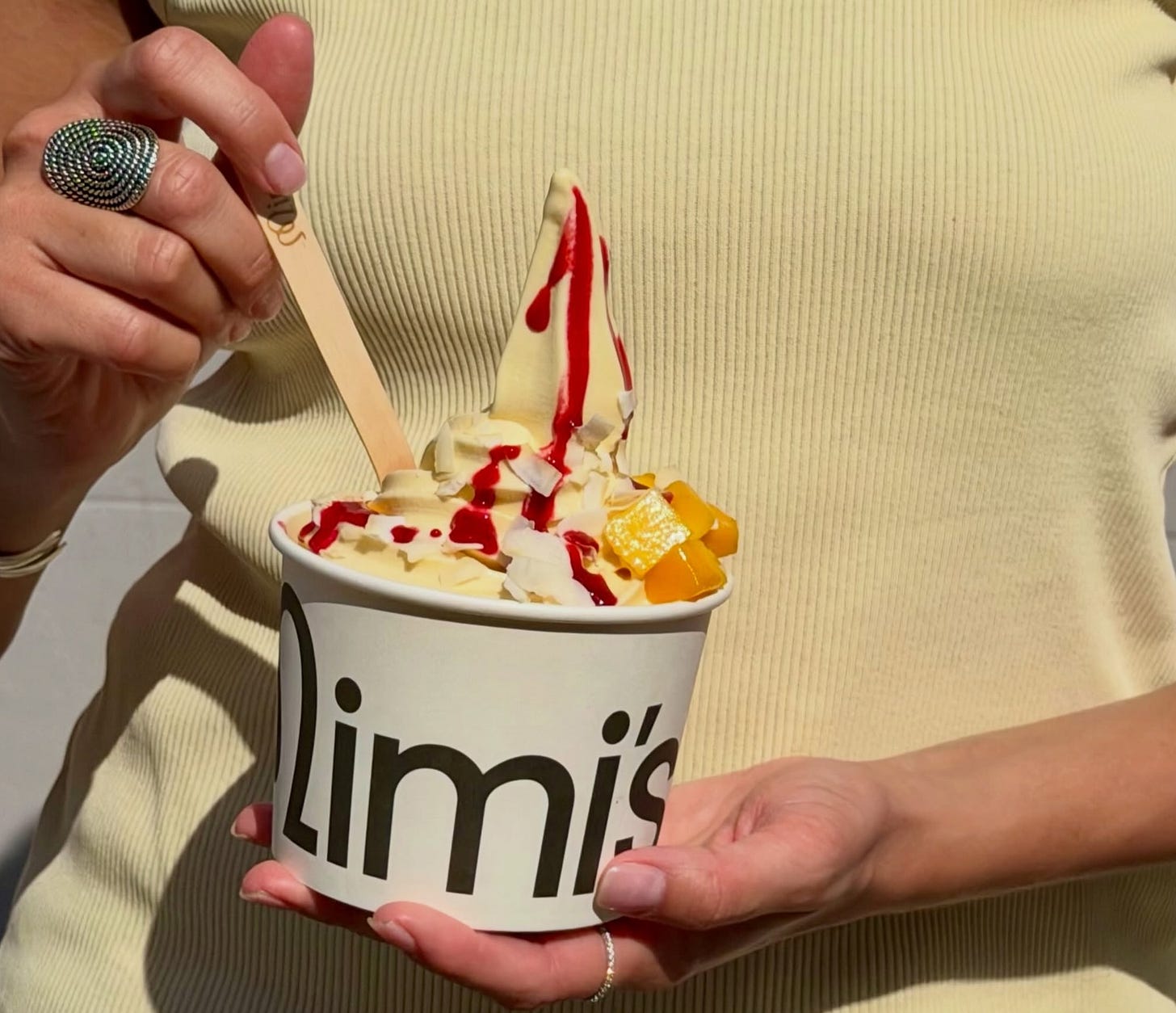 A close up shot of a woman holding a cut of frozen yogurt with toppings A close up shot of a woman holding a cut of frozen yogurt with toppings