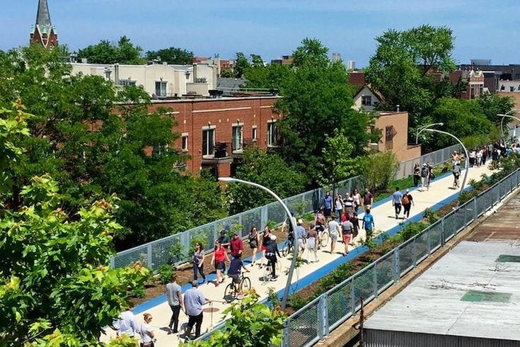 This may contain: many people are walking on the sidewalk near some buildings and trees in the city area