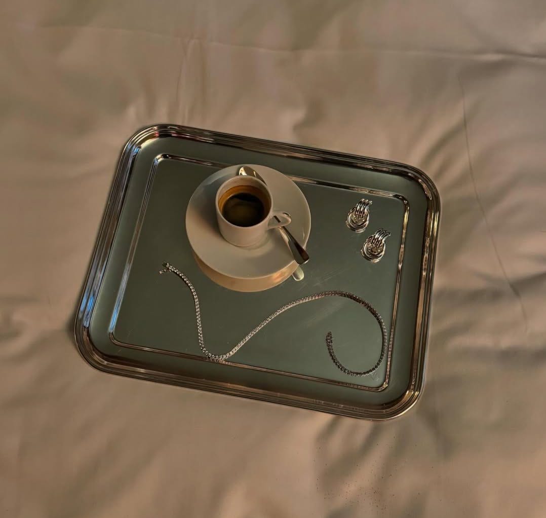 A tennis necklace on a silver tray with a coffee.
