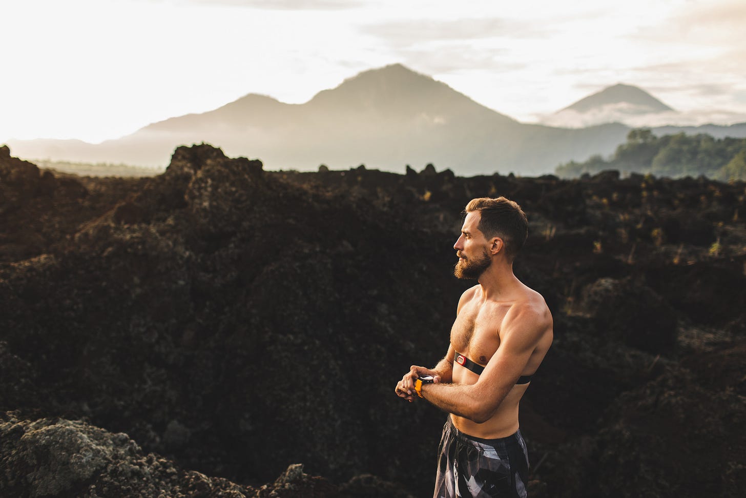 Shirtless man running in the mountains checking his smart watch and wearing a chest strap heart rate monitor. Shirtless man running in the mountains checking his smart watch and wearing a chest strap heart rate monitor.