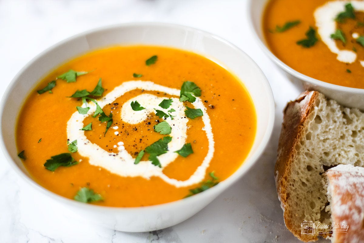 Bowl of carrot and corinader soup garnished with v swirl of cream and chopped parsley