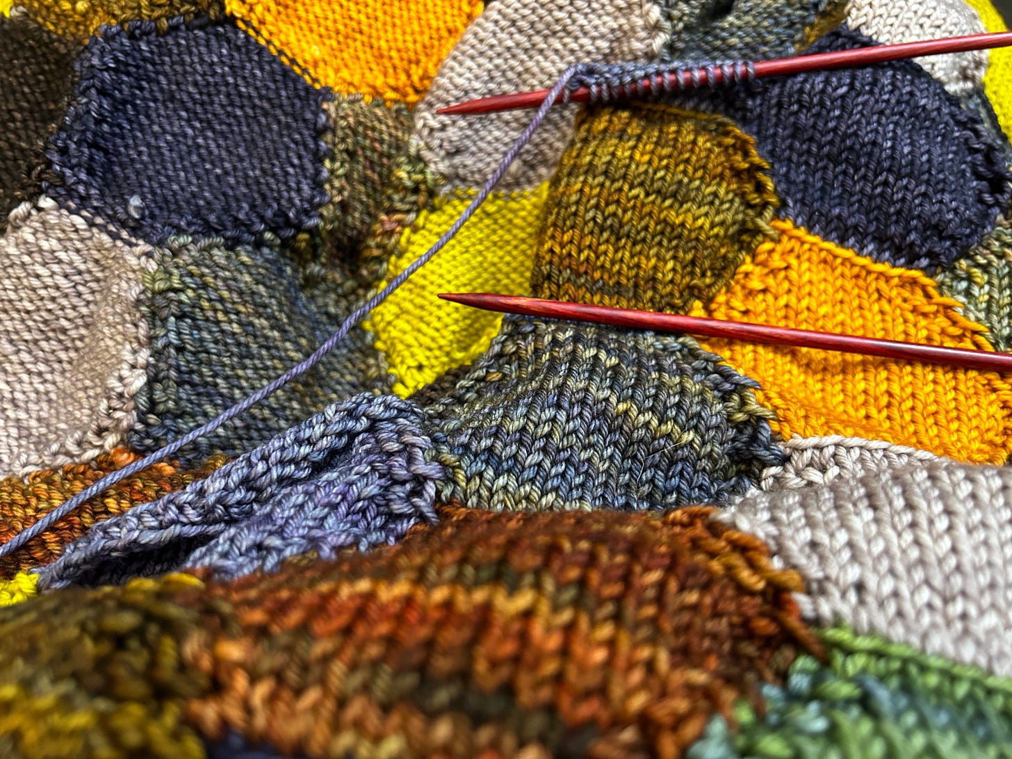 In progress knitted afghan made of connected hexagons. Colors are a muted fall palette. In progress knitted afghan made of connected hexagons. Colors are a muted fall palette.