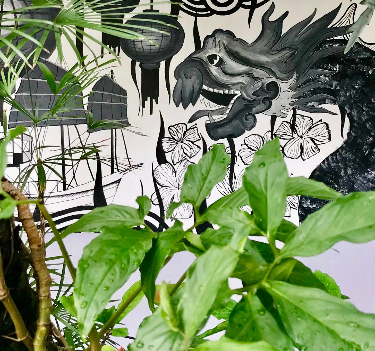 A painting or collage with leaves of a houseplant, a sampan, and a dragon