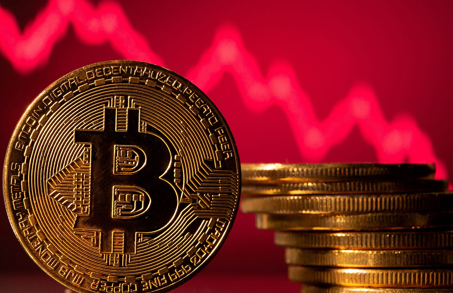 A representation of bitcoin is seen in front of a stock graph in this illustration