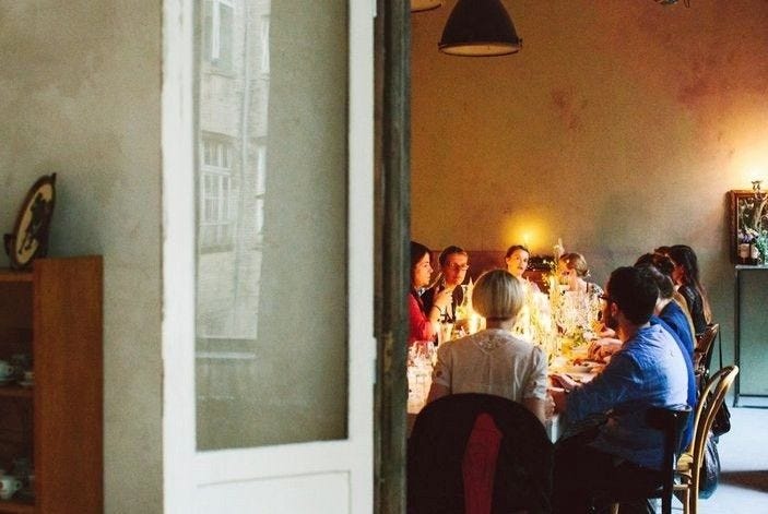 This may contain: a group of people sitting around a dinner table