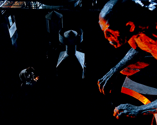 Image of a gargoyle on top of a building while two figures are below on the roof, one being examined by the other for injuries. Image of a gargoyle on top of a building while two figures are below on the roof, one being examined by the other for injuries.