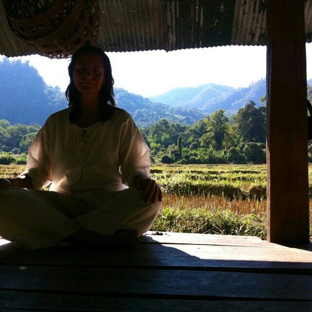 This may contain: a woman is sitting in the middle of a yoga pose with mountains in the background