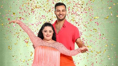 Ellie wears a peach fringed dress with long bejewelled sleeves while vito wears a pink shirt and orange trousers