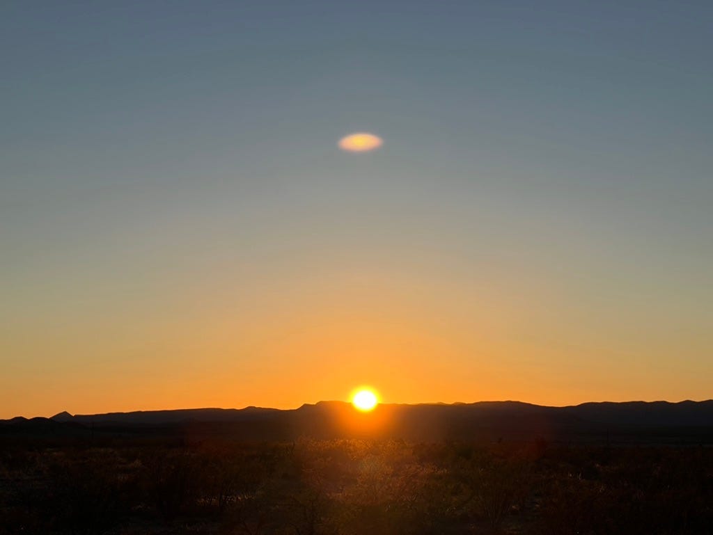 A sunset over a desert

Description automatically generated