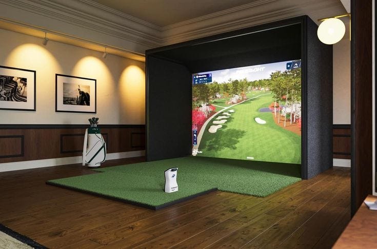 This may contain: a golf simulator is set up in the middle of a room with wood floors and pictures on the walls This may contain: a golf simulator is set up in the middle of a room with wood floors and pictures on the walls