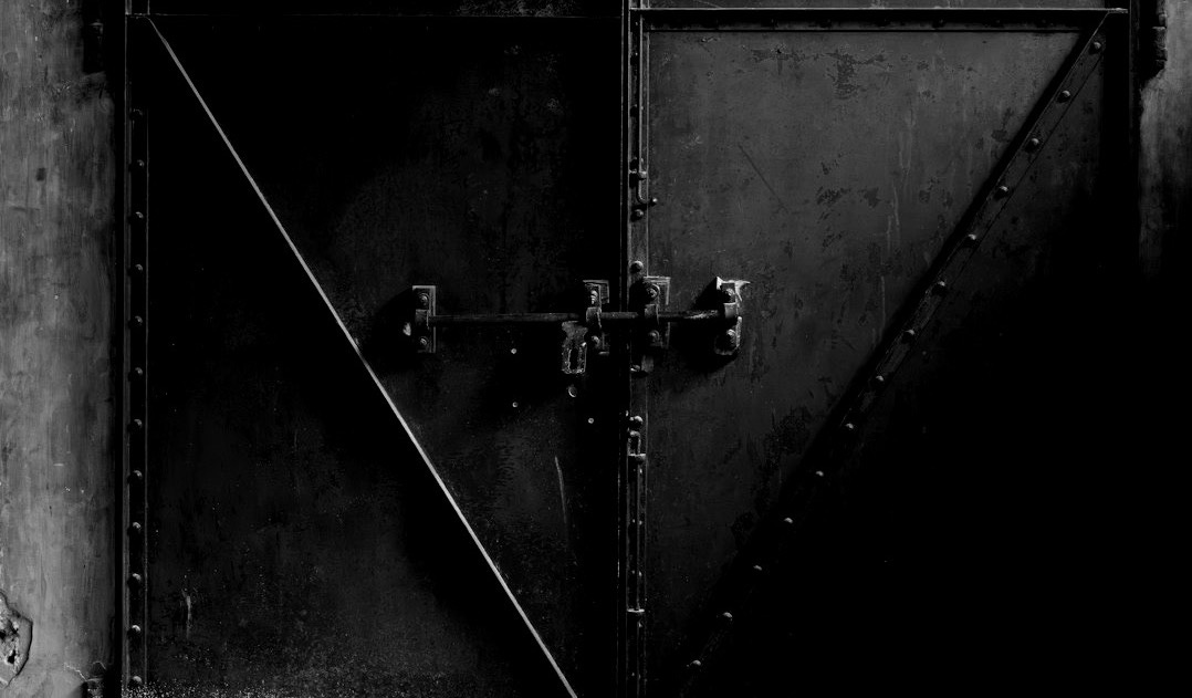 Rusty metal doors secured inside a worn building.
