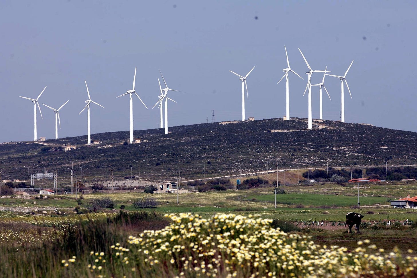 Wind turbines on hill behind agricultural land Wind turbines on hill behind agricultural land