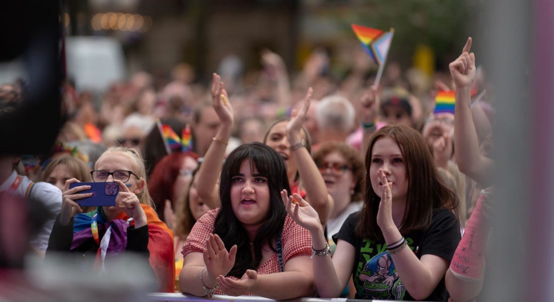 A crowd of people standing in front of a stage waving Pride flags at Notts Pride