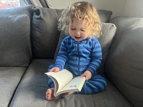 A toddler flipping through a paperback copy of GOOD GRIEF.