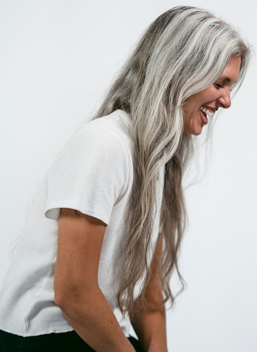 a woman with long white hair sitting on a stool